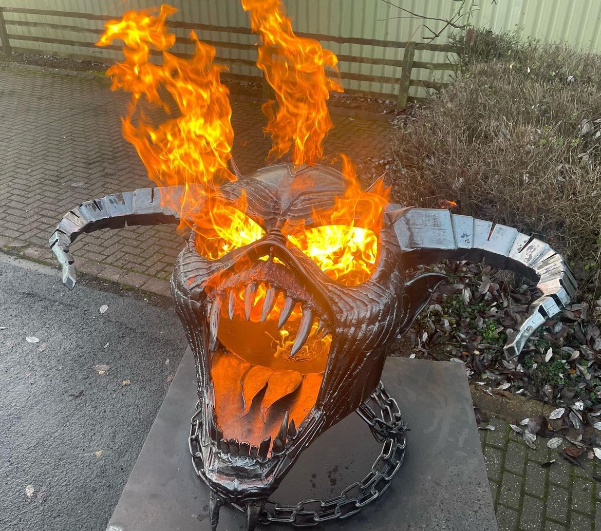 A custom made fire pit in the form of a skull with horns, with fire burning from the face